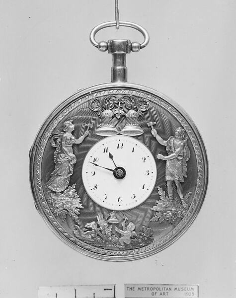 Black and white museum photograph of a silver watch with figures around the dial