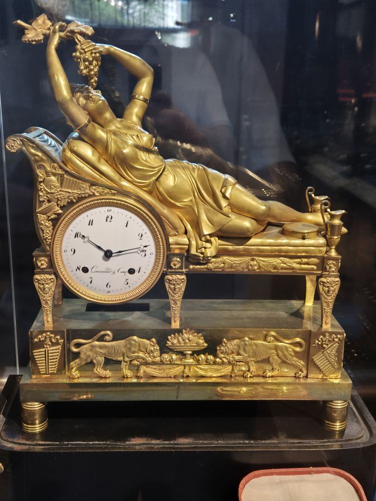 Gilt-bronze figural clock with a reclining figure above a white enamel dial signed Courvoisier